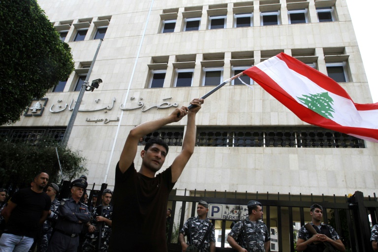 متظاهر يحمل العلم اللبناني خلال تظاهرة أمام المصرف المركزي فرع صيدا في جنوب لبنان في 28 أكتوبر 2019