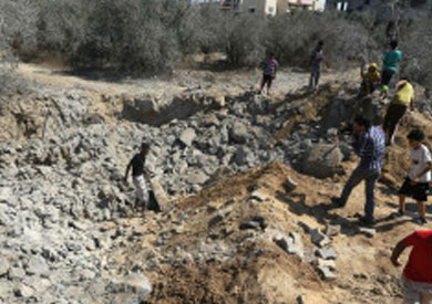 صورة أرشيفية لفلسطينيين يفحصون موقع غارة إسرائيلية في قطاع غزة
