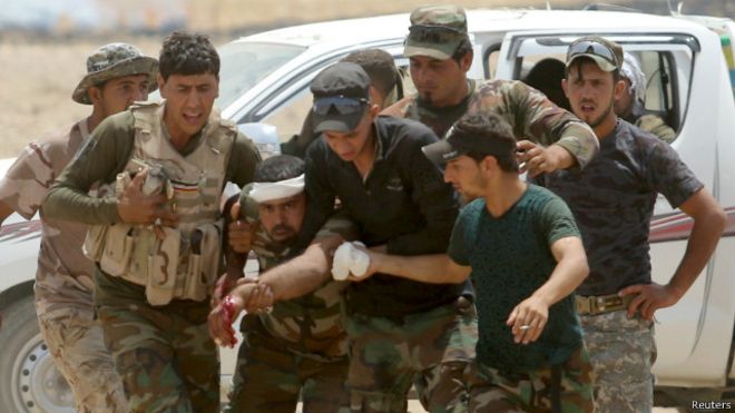 بعض أفراد قوات الحشد الشعبي يساعدون أحد الجرحى في اشتباكات مع مسلحي تنظيم الدولة الإسلامية.