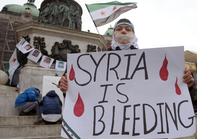 ناشطة تحمل لافتة كتب عليها «سوريا تنزف»